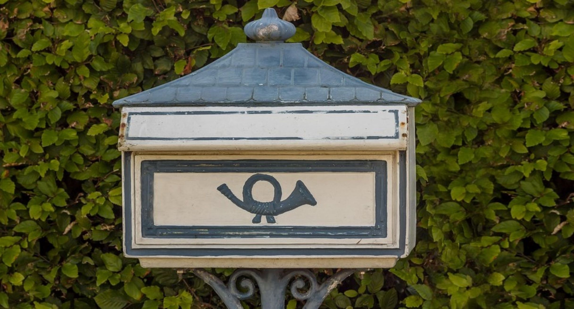 Briefkasten vor einer Hecke.
